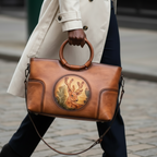 Sac en cuir bleu avec anses rondes, orné d’un médaillon illustrant un cerf stylisé, représentant le modèle Cervus Heritage