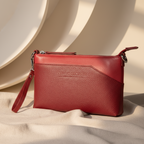 Pochette en cuir rouge lisse au format compact, dotée d’une fine bandoulière et pensée pour accompagner élégamment une soirée. 